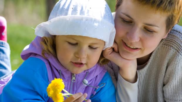 Mother and preschool-aged daughter holding dandelions