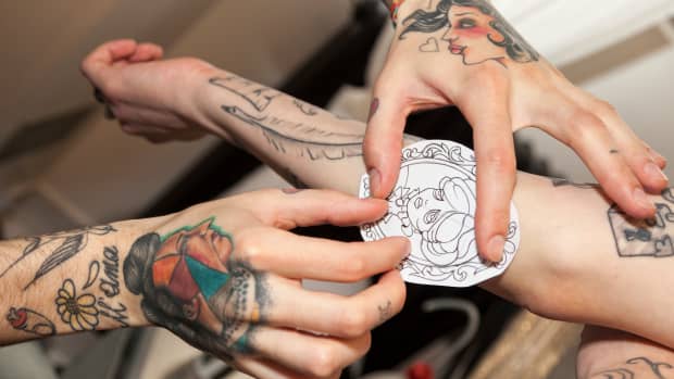 tattoo artist placing stencil