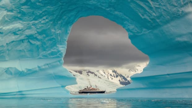 Ship seen through the hole of an iceberg in Antarctica