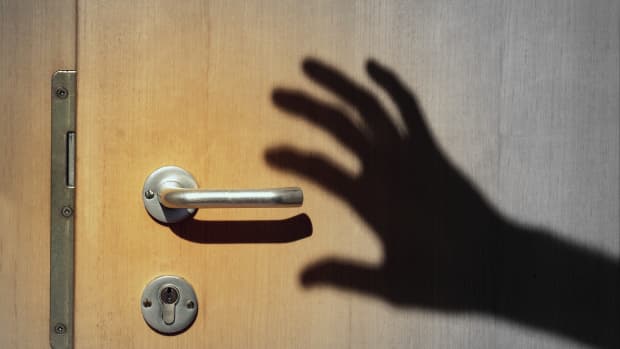 a shadow of a hand reaches out to a door handle