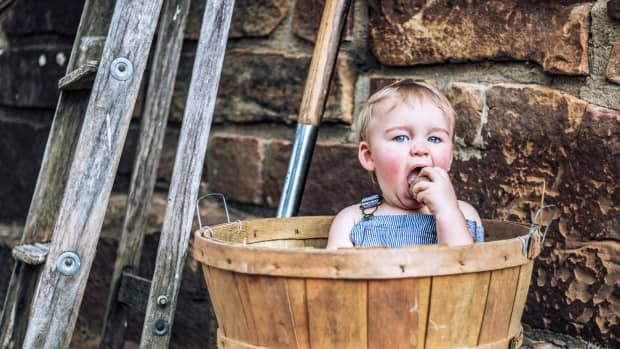 toddler boy sitting in wooden bucket