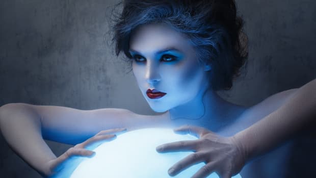 a woman with extremely pale skin clutches a glowing ball