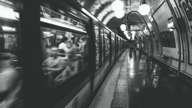 a stylized black and white photo of a pretty subway stations in Paris, France, with a train rushing past.