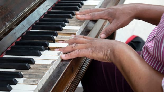 The hands of a man playing the keys of a public piano at Nottingham railway station
