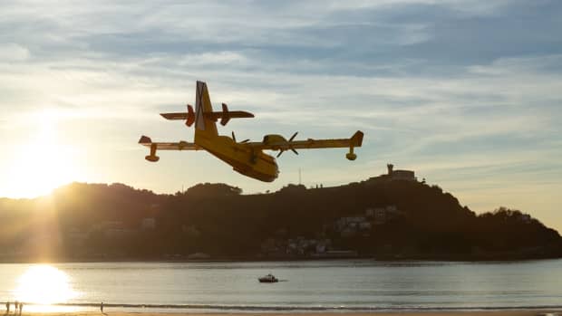 A fire fighting plane dips low to collect water at a beach