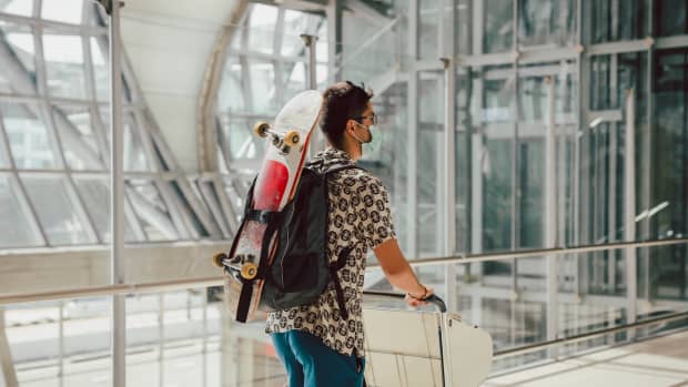 Young man walks through the airport with a skateboard strapped to his back