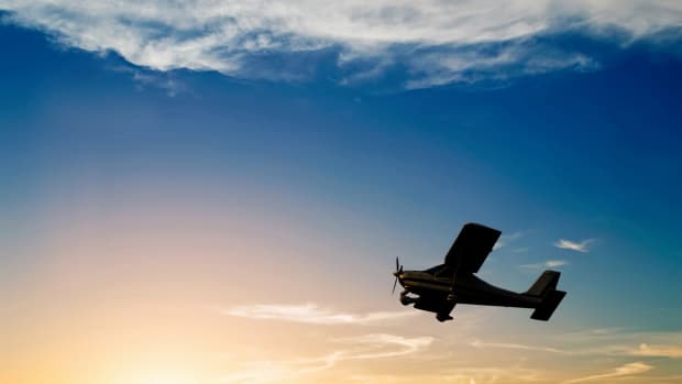 Silhouette of a single engine airplane flying at sunset