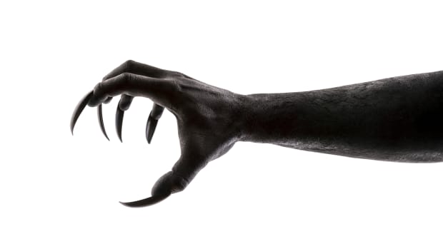 a hand with long creepy claws reaches out over a white background.