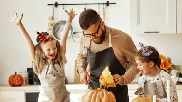 dad carving pumpkin with kids