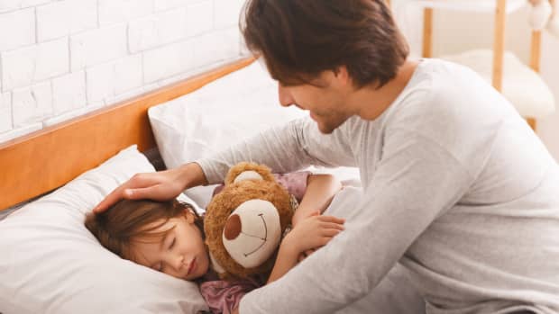 dad tucking child into bed