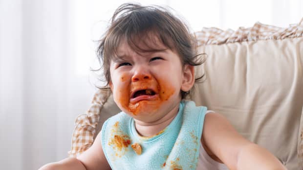 toddler crying with spaghetti sauce on face