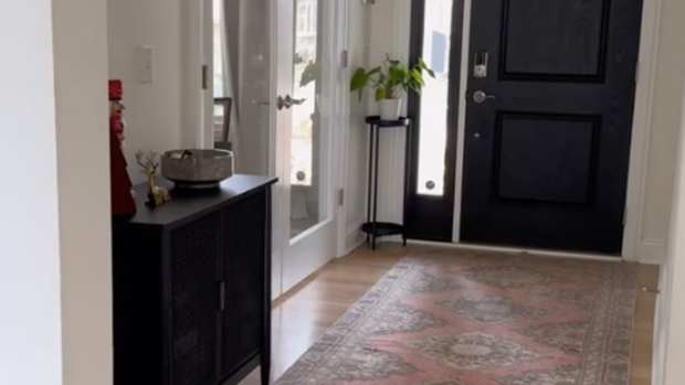 foyer with a black front door, black credenza, and a rug