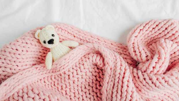 stuffed animal bear in pink baby blanket