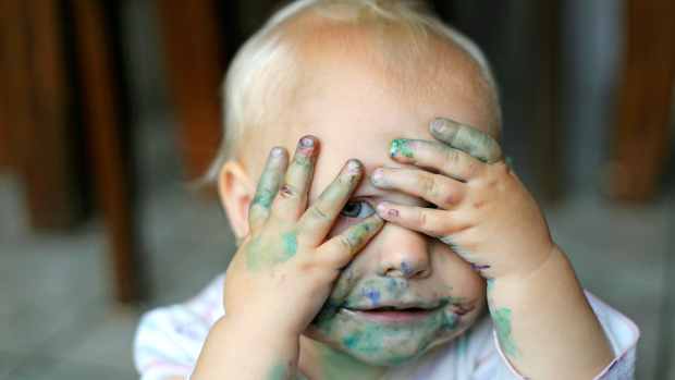 baby with paint on hands and face
