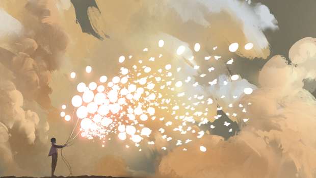 A person stands against a brilliant golden sky and releases glowing balloons that turn into sparkles