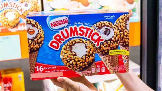 Shoppers hand holding a family size package of Nestle Drumstick sundae ice cream cone in a supermarket aisle