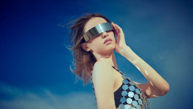 Fashion model poses in metallic dress with a silver band across her face.