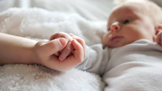 baby holding toddler's hand