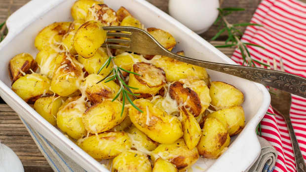 Roasted potatoes with melted cheese on top in a white casserole dish
