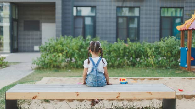 little girl sitting alone on playground