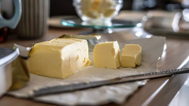 A stick of butter sitting next to butter cubes and a knife