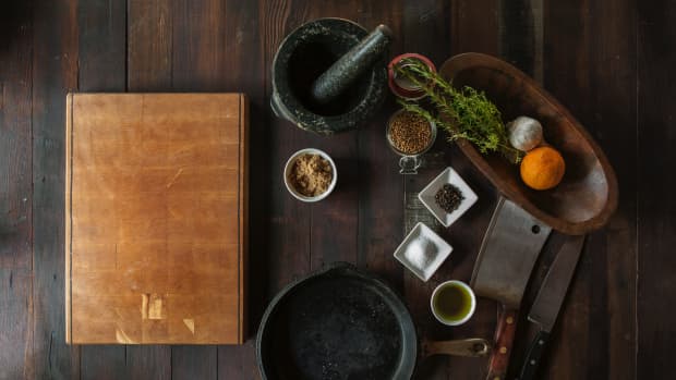 Wooden cutting board, cast iron skillet, knives, spices, and other prepping utensils