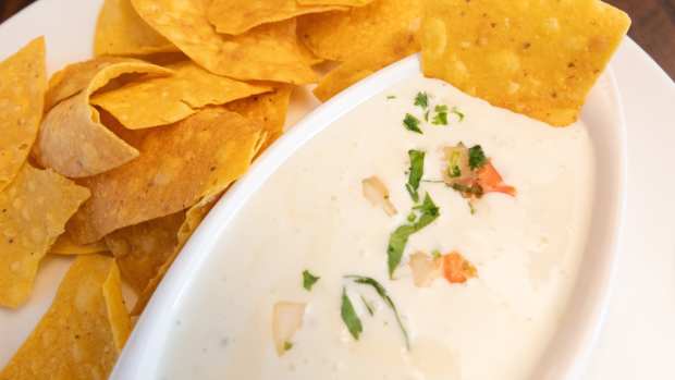 A bowl of warm queso served with tortilla chips.