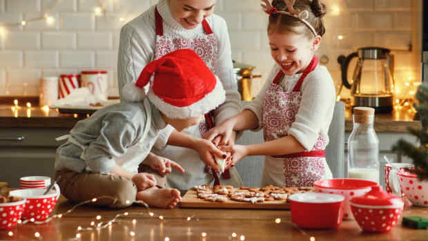 A mother with her two children making Christmas cookies in the kitchen.