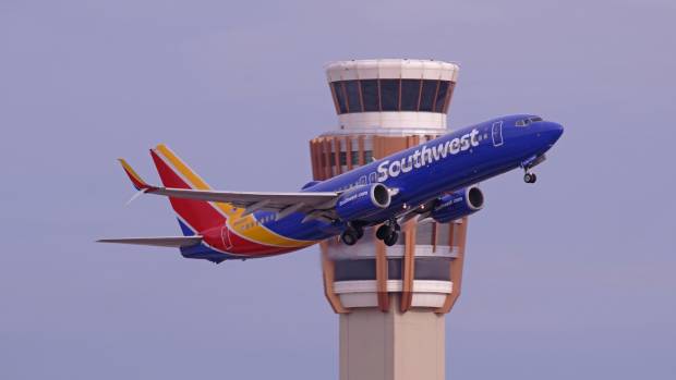 A Southwest Airlines plane flying past an ATC tower in PHX