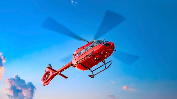 A red EMS helicopter flying overhead