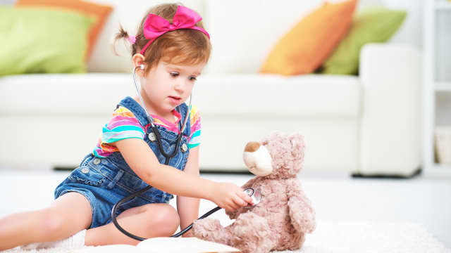 toddler little girl playing doctor with stuffed bear