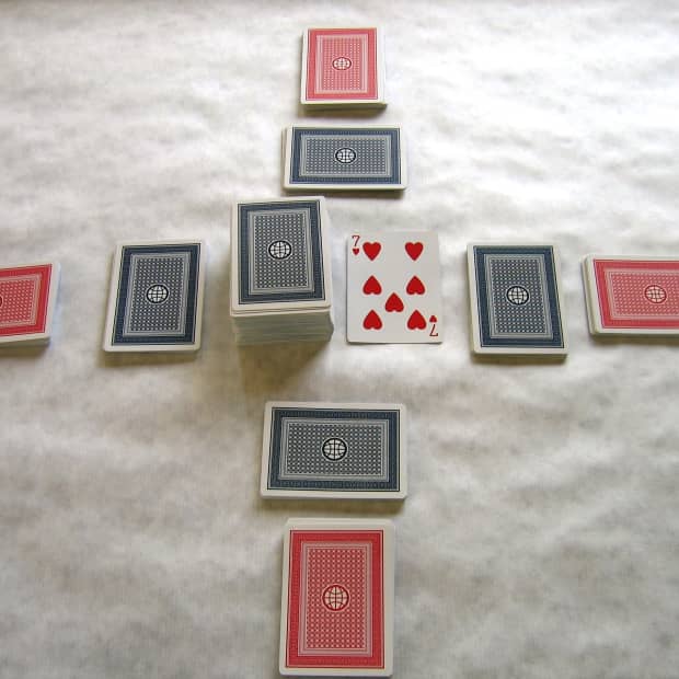 The table is set for play. Front hands in red, back hands in blue. The pick up and discard piles are in the center. Players may only look at their front hand cards first, and may not look at the back hand until they have played through the front hand