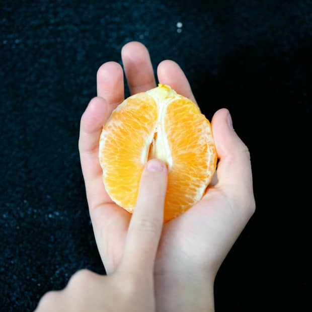 Hand holding half an orange.
