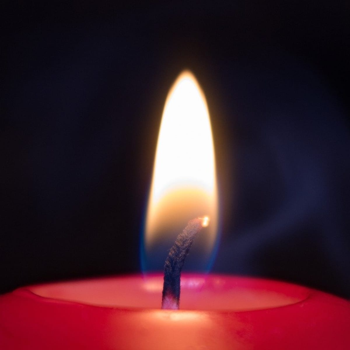 Burning candle with melting wax close-up on a black background