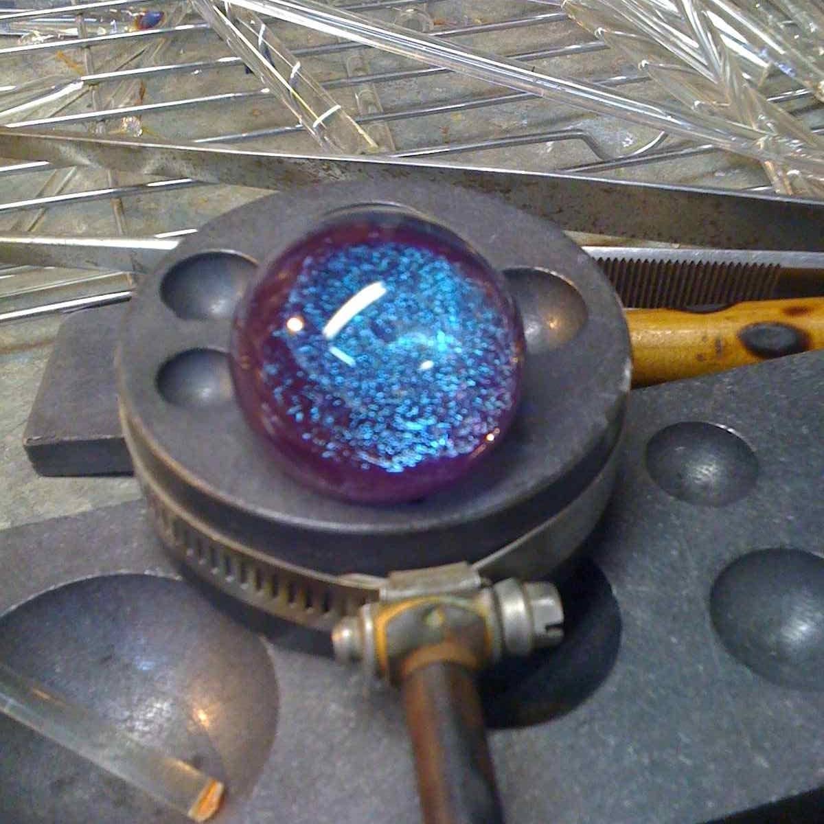 Glass blower crafts marbles and pendants
