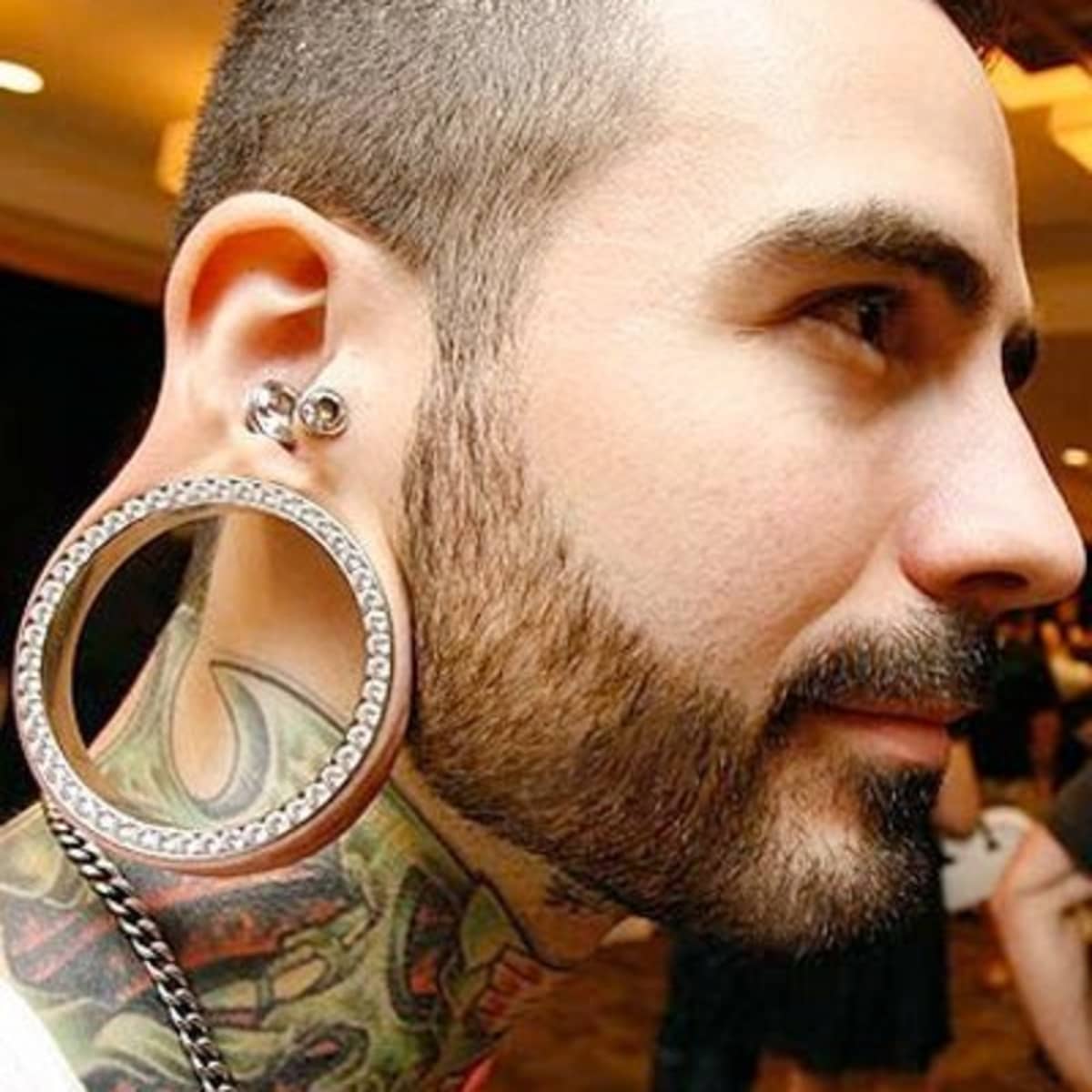 Close-up image of a person with beautifully stretched ear piercings adorned with decorative plugs, illustrating the art and appeal of ear gauges.