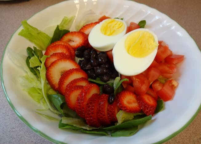 Boiled egg, strawberries, black beans, tomatoes, spinach, and iceberg lettuce