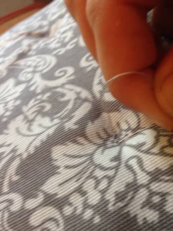 Thread is gently, but tightly, pulled to create an indent in the cushion.
