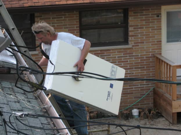David carries foam sheeting to lay on top of the old asphalt shingles 