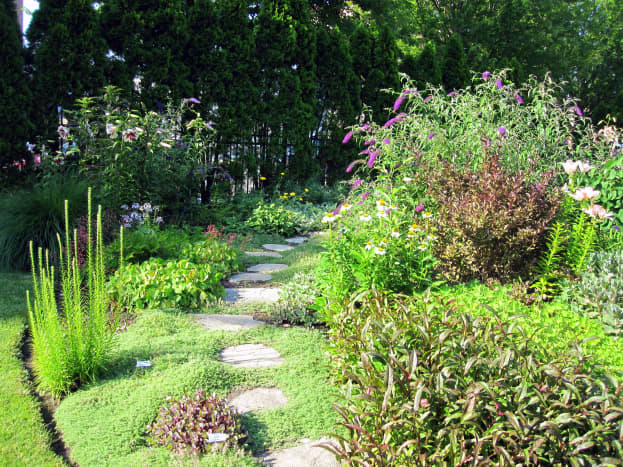 A flagstone path beckons visitors to explore around the bend of the perennial border.