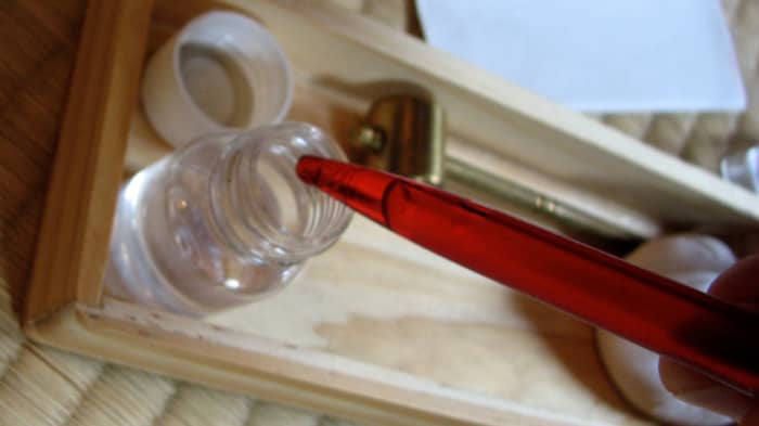 Using an empty, clean pen as an eye dropper to put the choji oil on the katana blade.