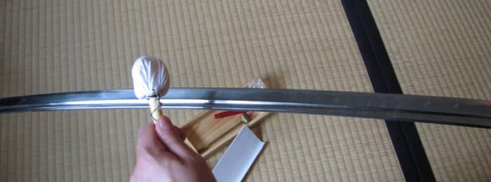 Tapping the uchiko along the katana blade.