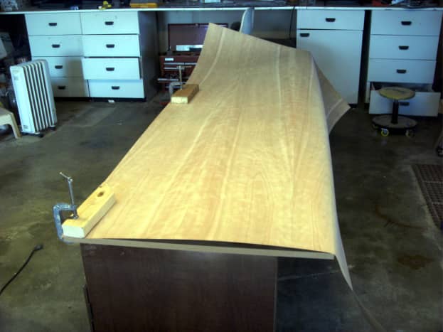 The veneer is clamped to the desktop to mark for cutting