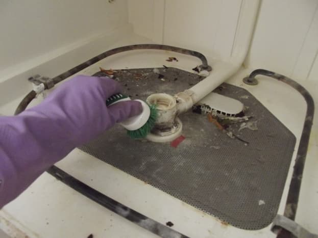 Scrub the bottom of the dishwasher to dislodge debris and mineral deposits.