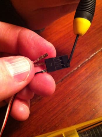 With a small screwdriver, gently release the tab holding the wires in place.
