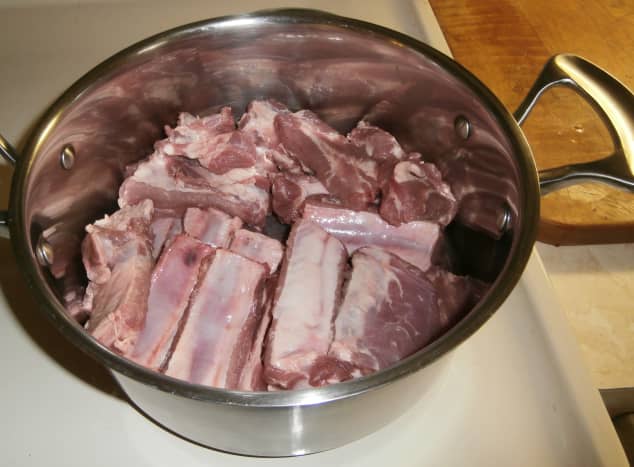 After cutting the rack of ribs into individual ribs or into quarters, place the ribs into a pot. 