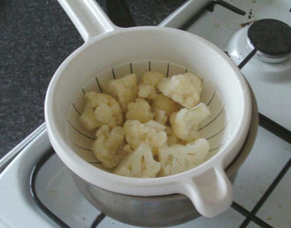 Boiled cauliflower florets are drained and left to steam