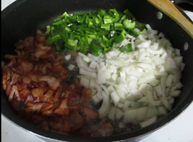 After bacon is browned, move the bacon to the side and add onions and peppers to the bacon grease left in the pan, allowing the onions and peppers to caramelize, or brown slightly.