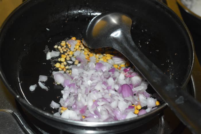 1. Heat oil in a deep-bottomed pan. Add mustard seeds. Once they splutter, throw in gram dal and white lentils. Saute them till they become golden brown. Add onions.