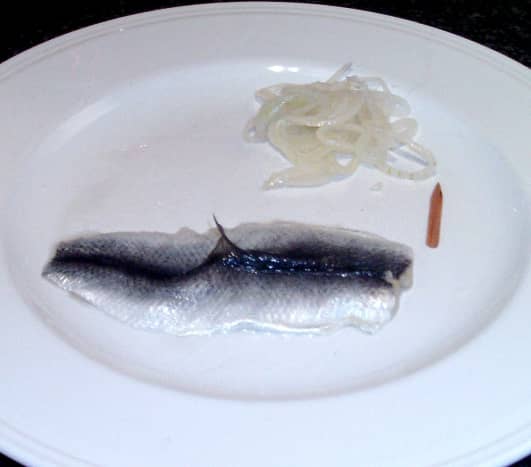 Unwrapped pickled herring or rollmop with dangerously protruding fin